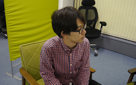 座って左を向くプログラマの松村さん