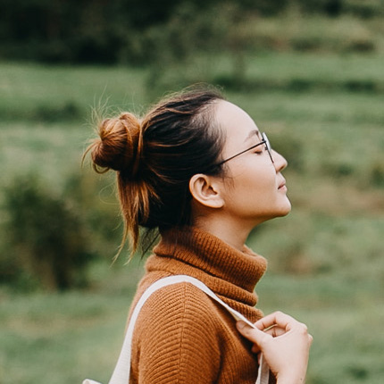 ' . __( 'A side profile of a woman in a russet-colored turtleneck and white bag. She looks up with her eyes closed.' ) . '