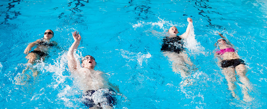 Tre svømmere i baseng